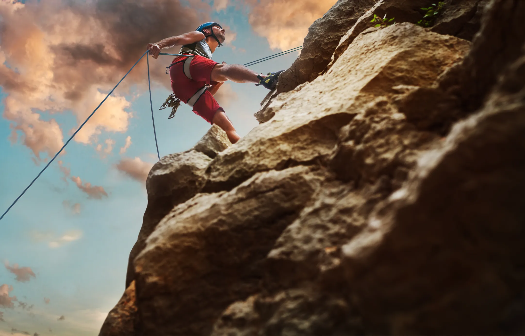 Rock climber ascending a steep cliff face at sunset